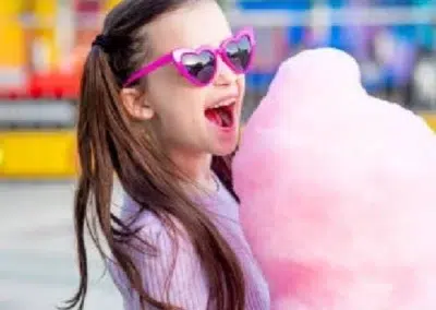 Fille avec lunettes de soleil et barbe à papa rose