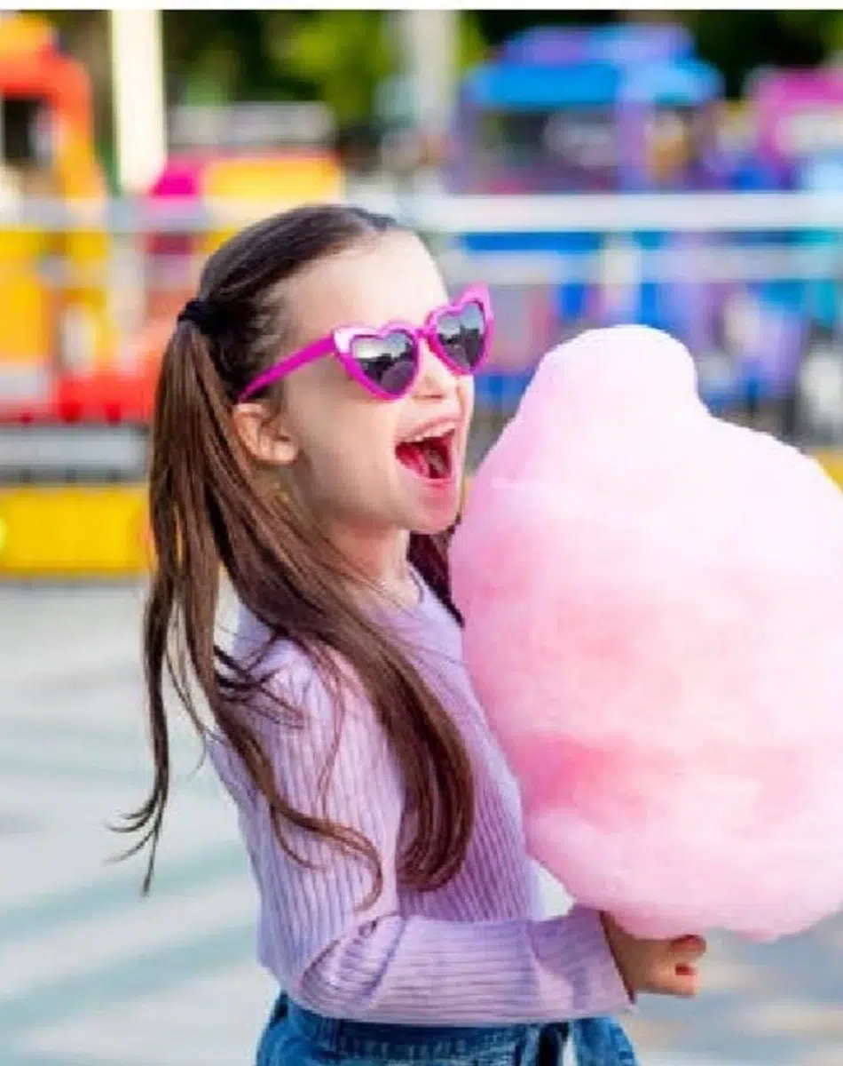 Fille avec lunettes de soleil et barbe à papa rose