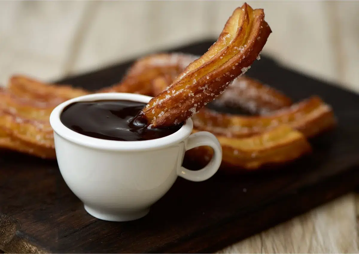 Churros avec sauce au chocolat dans une tasse blanche
