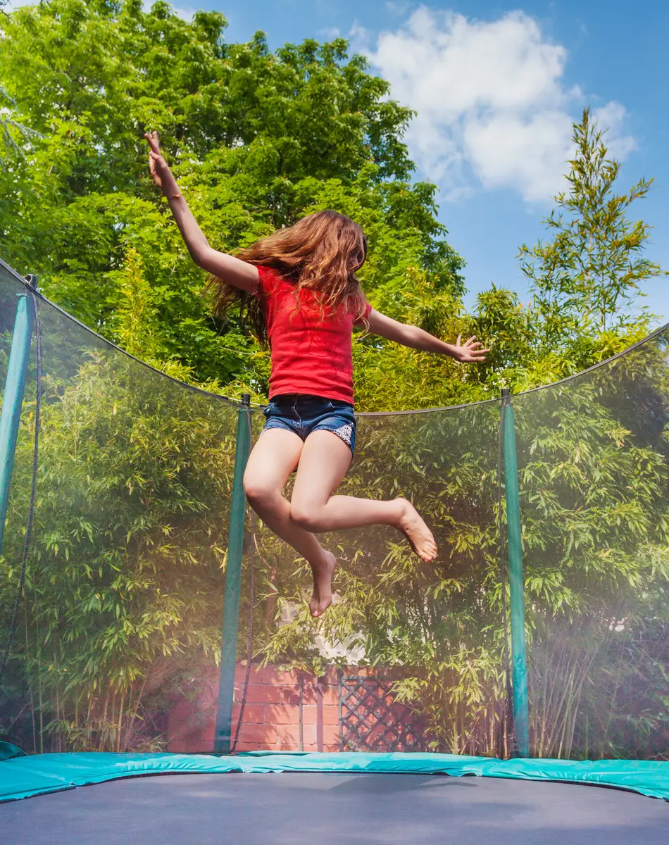 Enfant sur trampoline dans le jardin Enfant sautant sur un trampoline en plein air.
